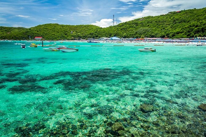 A turquoise ocean with small boats and hills in the background - Thai Pass