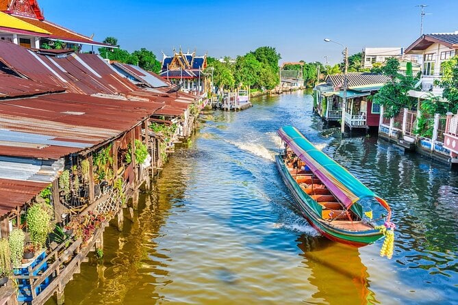 A long tail boat passing the houses built alongside the canal - Thai Pass