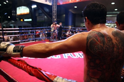 A man with tattoo on his back standing in a boxing ring - Thai Pass