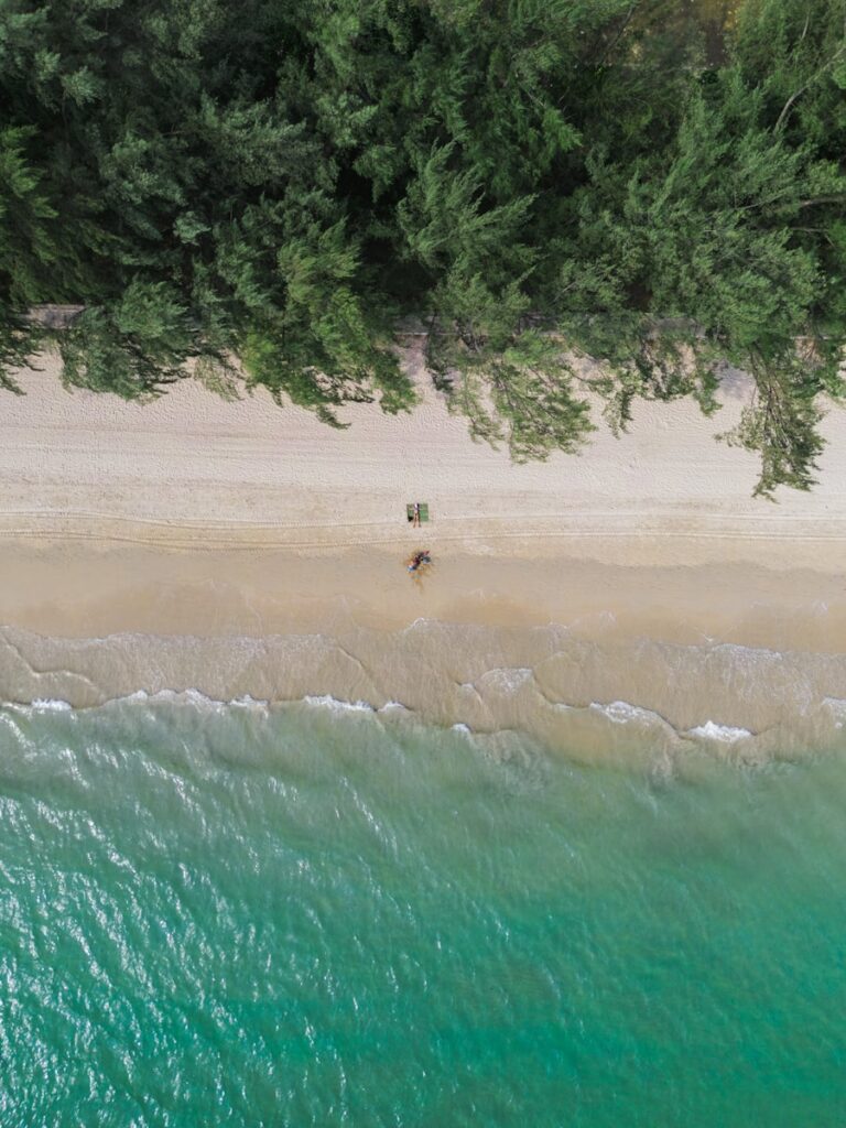 An aerial view of a beach with two people on the Railay Beach - Thai Pass