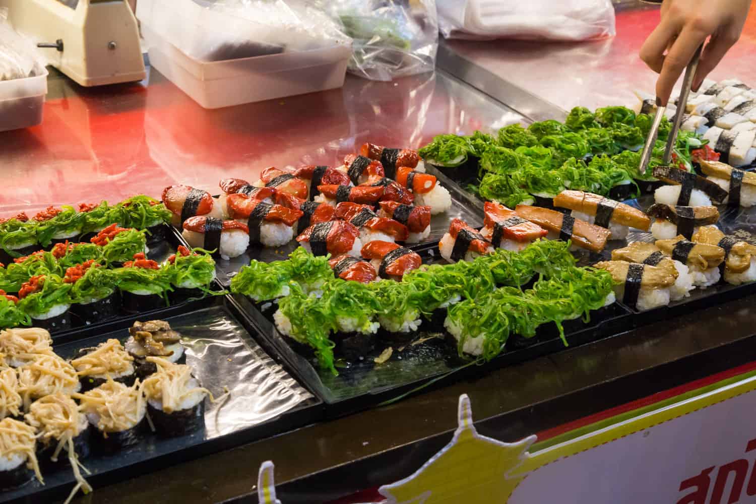 A variety of sushi pieces are displayed on a market stall - Thai Pass